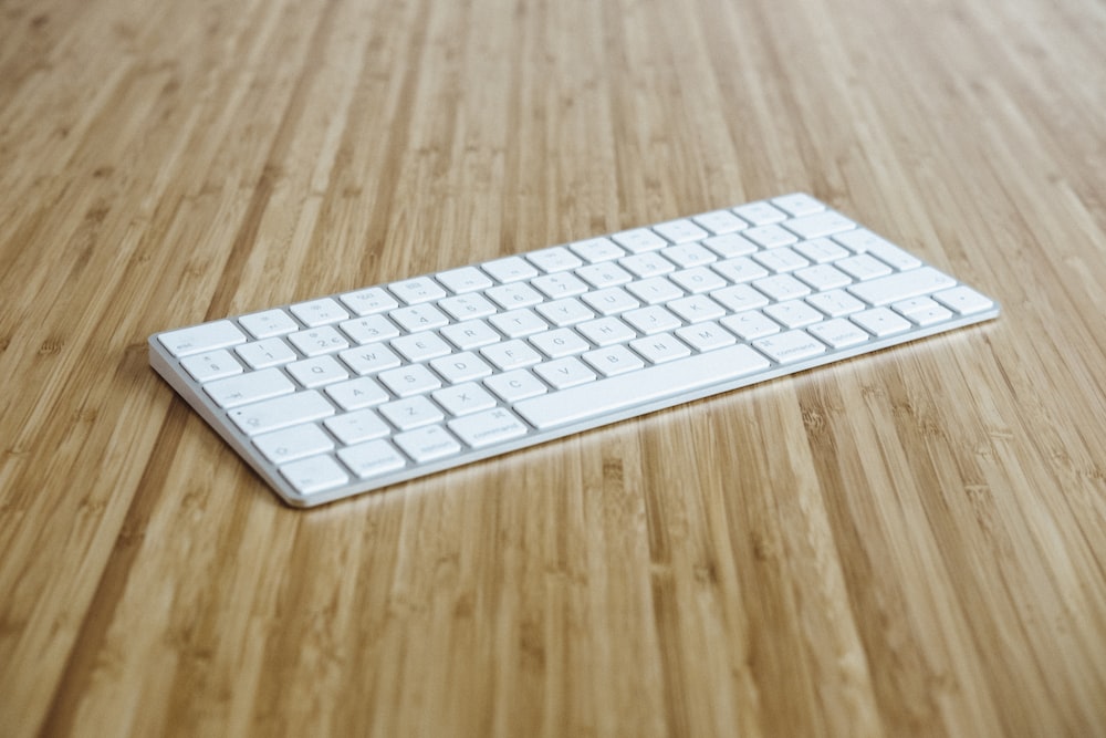 Teclado plateado y blanco sobre superficie de madera marrón