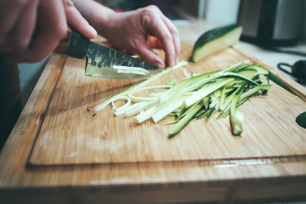 person slicing cucumber