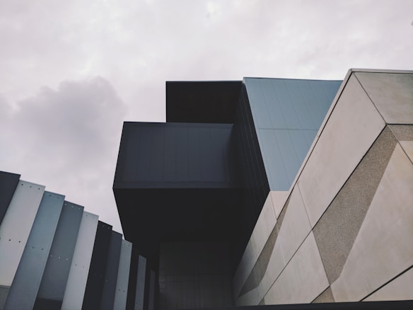 A modern architectural structure featuring clean lines, geometric shapes, and a mix of materials. Overcast sky enhances the overall minimalist aesthetic.