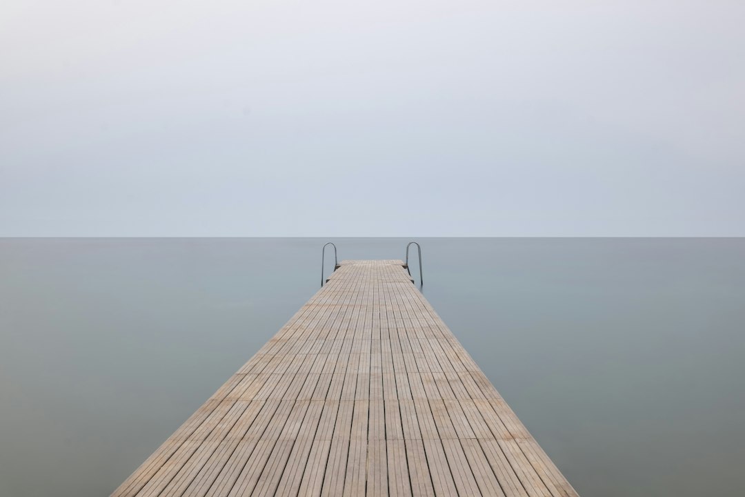 brown wooden dock with cloudy sky,
