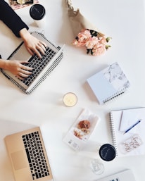A serene workspace featuring a laptop displaying a nikahnama design alongside delicate wedding flowers.
