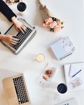 A creative workspace with laptops, notebooks, and coffee cups.