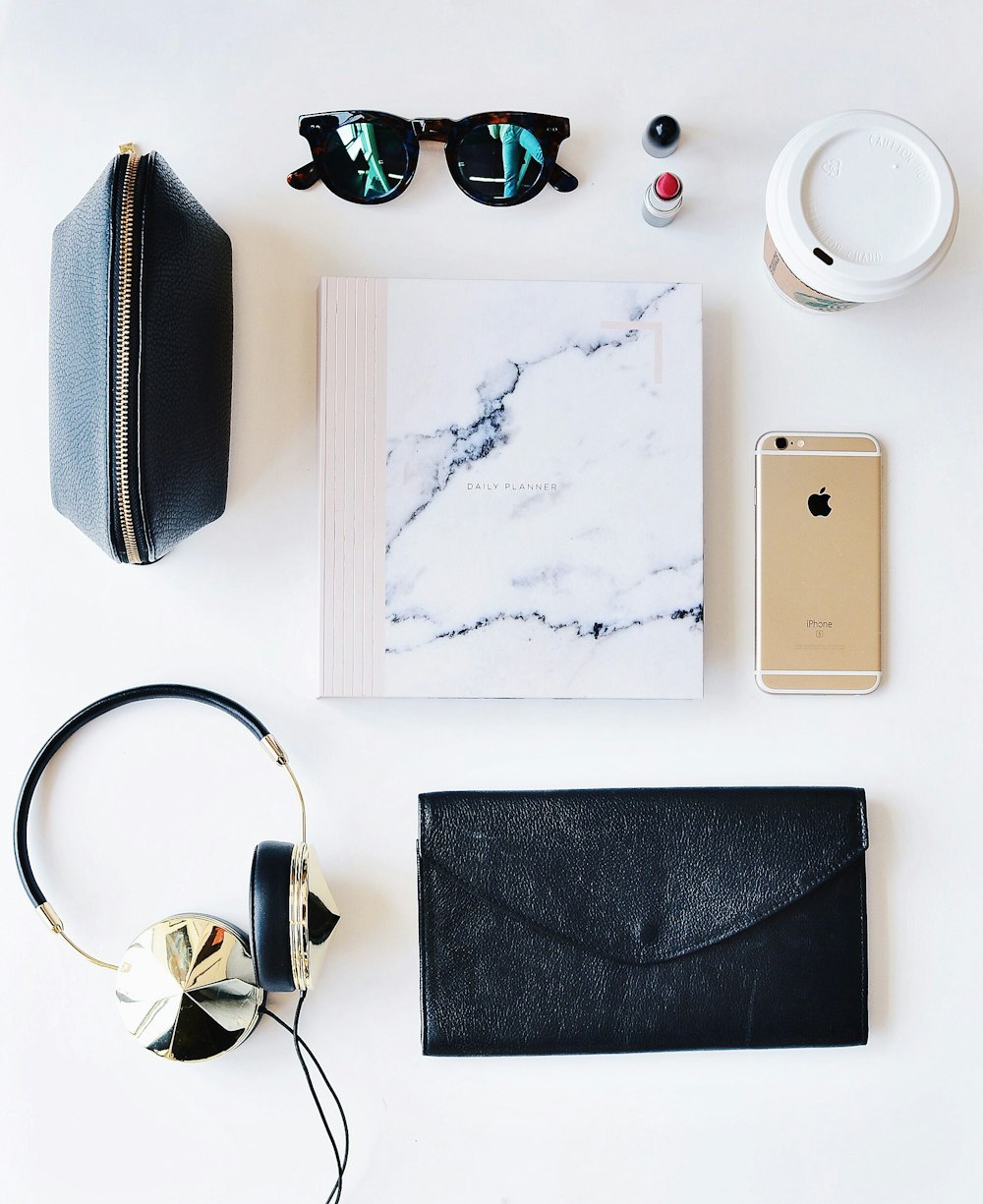A flatlay image of paper, a smartphone, cup of coffee, glasses and various other items.