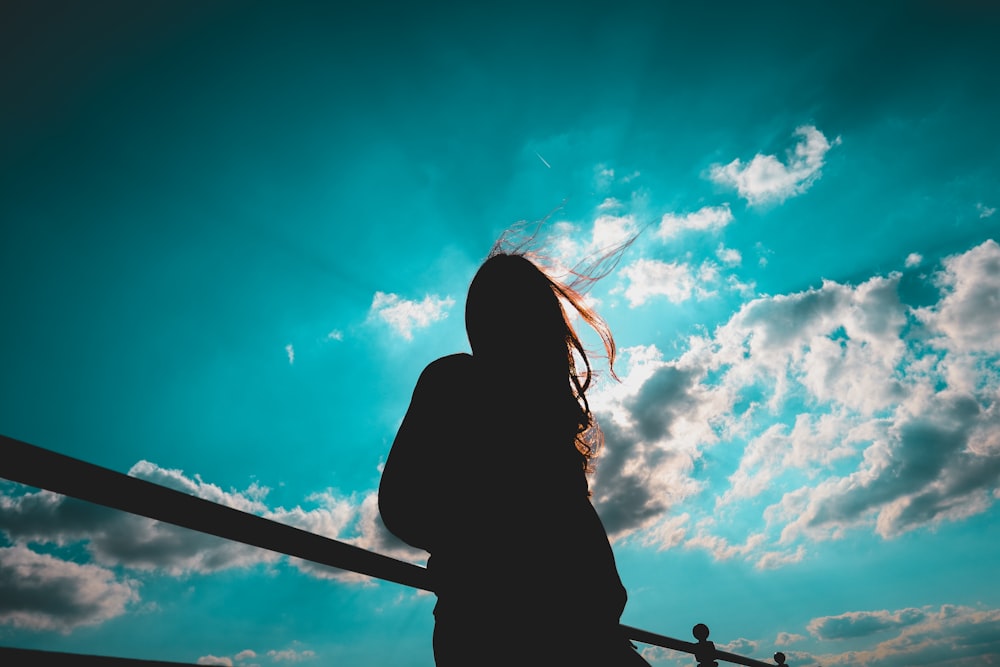 silueta de mujer de pie con cielo nublado