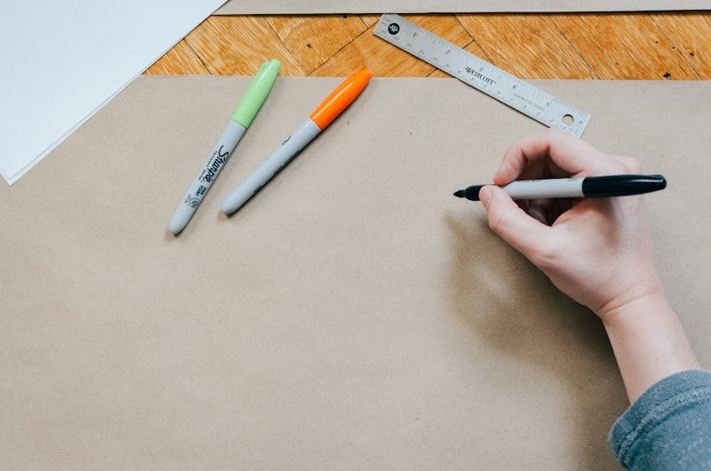 A hand sketching with markers on kraft paper