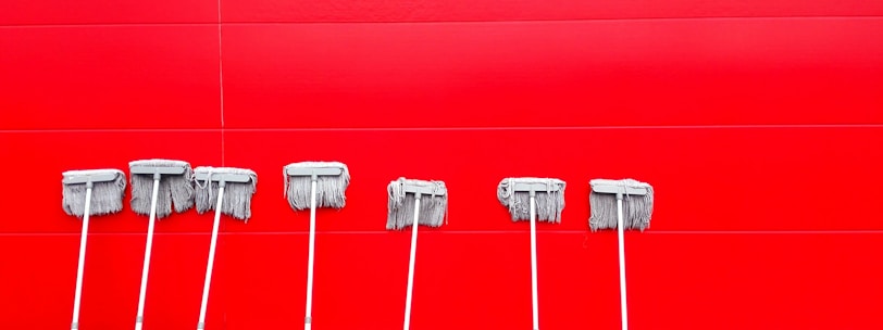 seven white push mops on wall