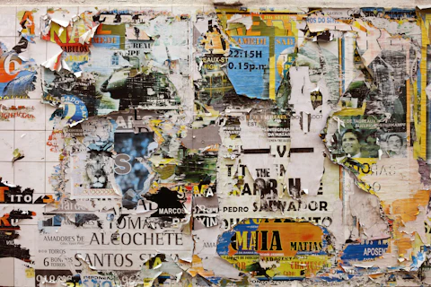 Layers of torn, weathered posters and flyers pasted over each other on a wall
