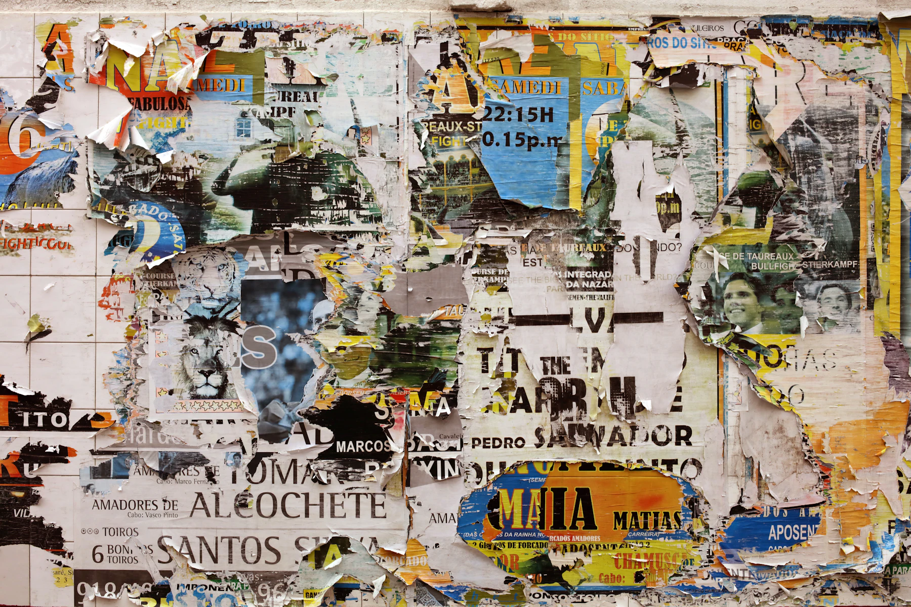 Layers of torn, weathered posters and flyers pasted over each other on a wall