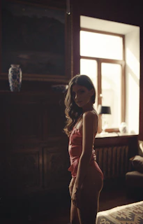 Nany Palacio Love posing gracefully in a cozy, softly lit room with pink accents