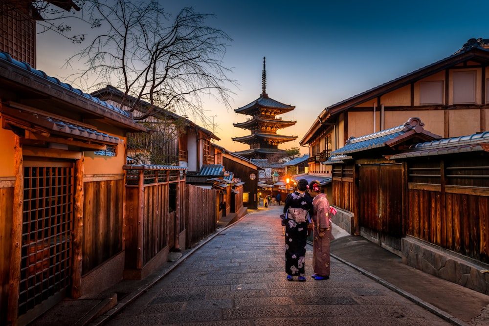 two women in purple and pink kimono standing on street