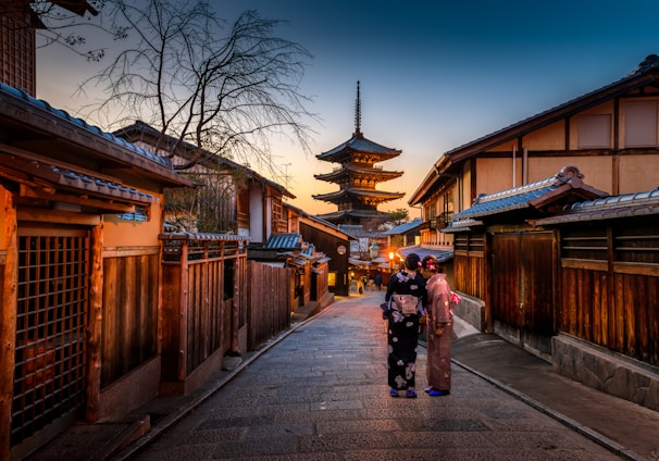 two women in purple and pink kimono standing on street