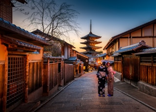 two women in purple and pink kimono standing on street