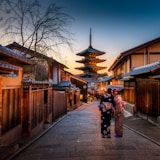 two women in purple and pink kimono standing on street