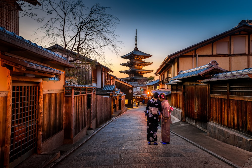 Dos mujeres con kimono púrpura y rosa de pie en la calle