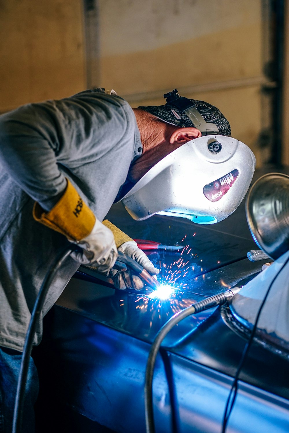 person with mask welding on vehicle