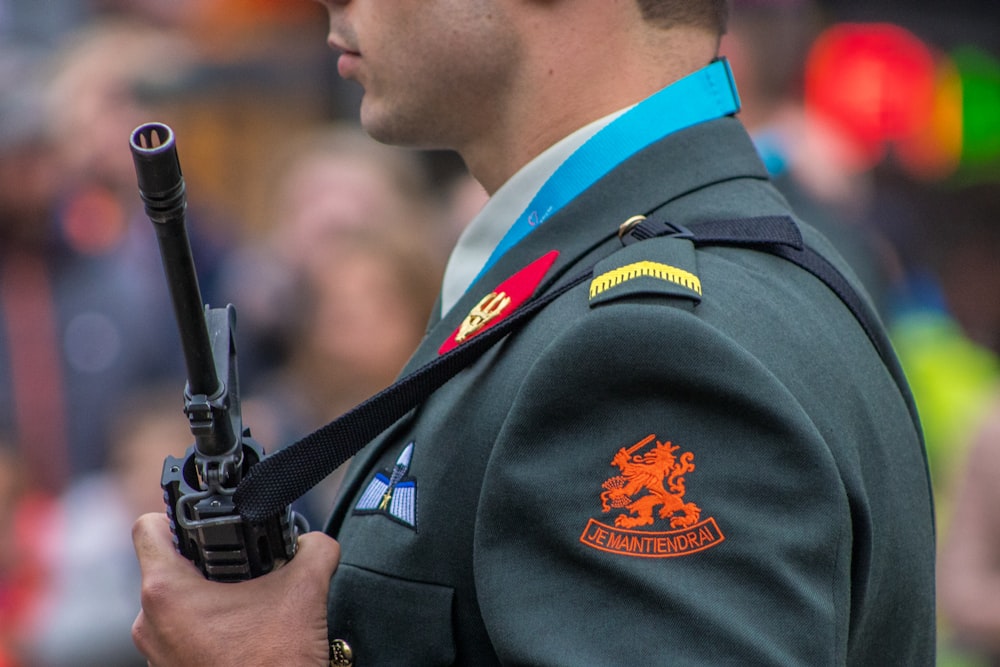 man holding rifle selective photography