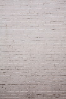 A plain wall made of light-colored bricks with a consistent and uniform pattern.