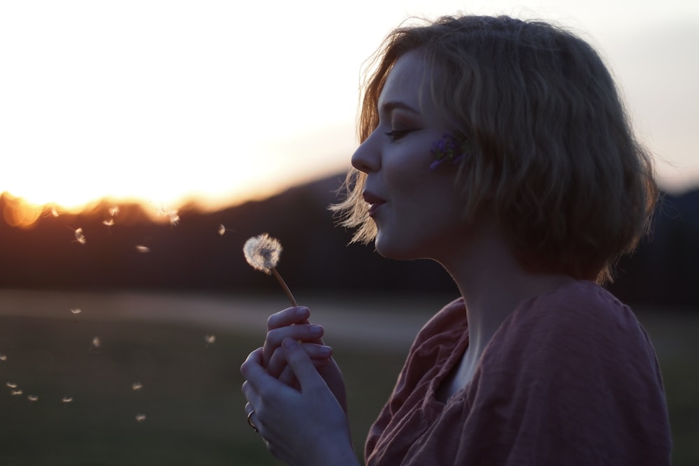 woman blowing dandelion flower selective focus photography