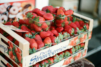Fresh strawberries being carefully packed for delivery in a rustic wooden crate.