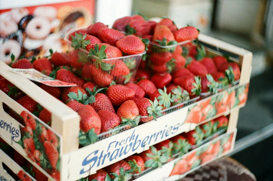 Fresh strawberries being carefully packed for delivery in a rustic wooden crate.