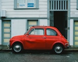 red Volkswagen Beetle car parked in front of white house