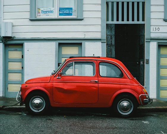 red Volkswagen Beetle car parked in front of white house