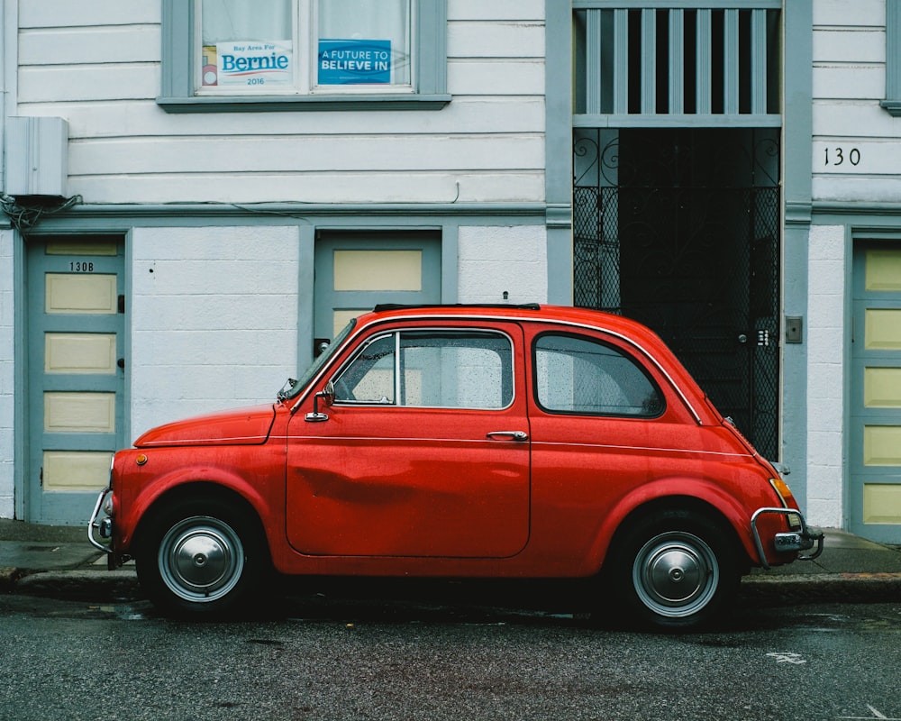 Coche Volkswagen Beetle rojo aparcado frente a la casa blanca