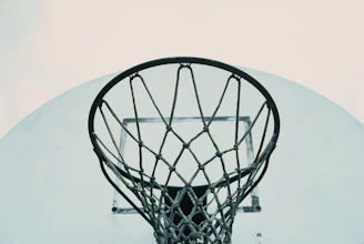 Close-up of a colorful braided basketball net with intricate patterns, hanging on a metal hoop.
