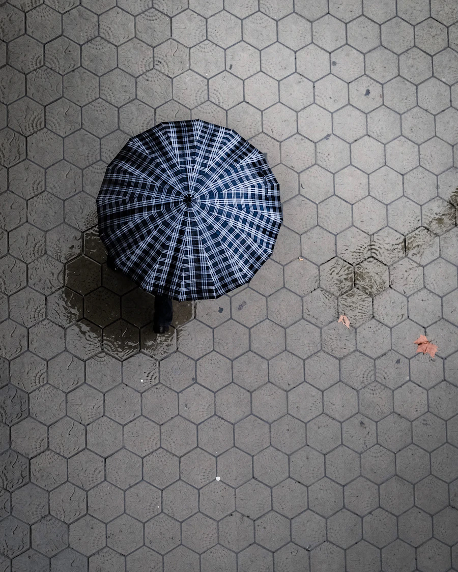 Plaid umbrella seen from above on a wet tile walkway