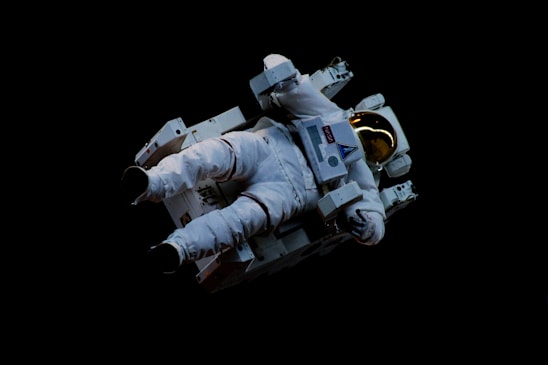 An astronaut wearing a white spacesuit floats in space, using a jetpack for maneuvering. The reflective golden visor of the helmet contrasts against the dark backdrop of space.