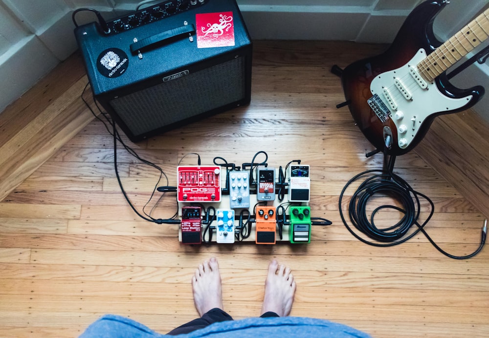 assorted guitar pedal lot beside electric guitar and amplifie