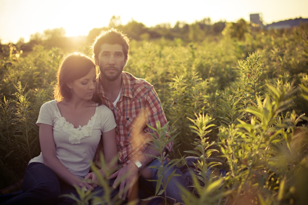 man and woman sitting on grass field at daytime