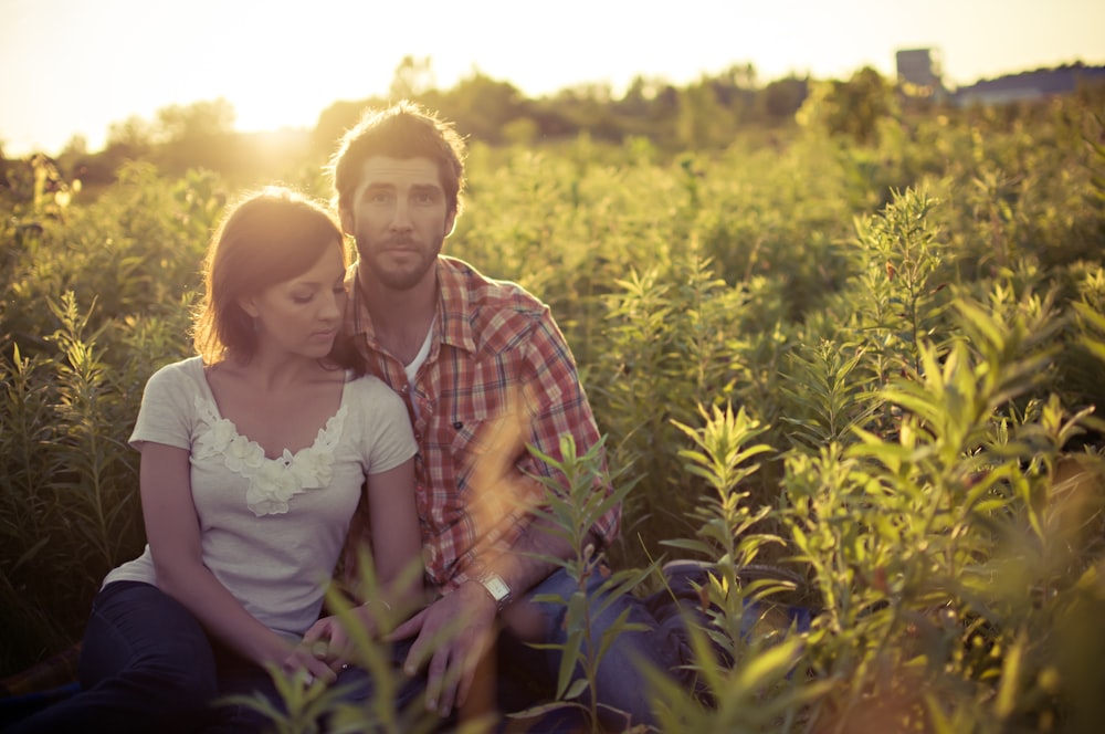 homme et femme assis sur le champ d’herbe à la journée