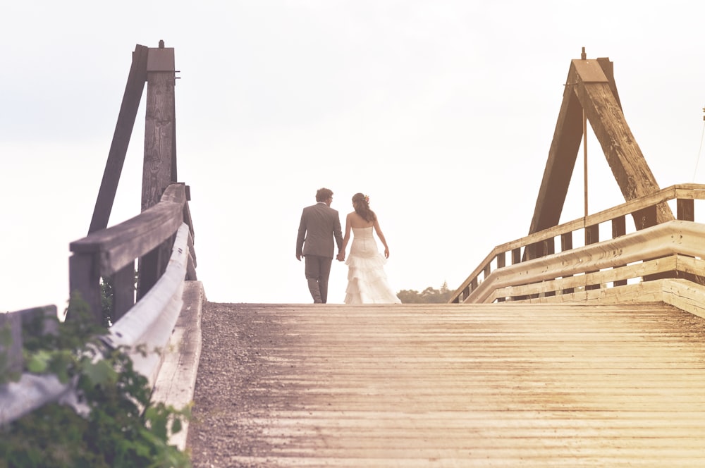 pareja de novios caminando en medio del puente de madera