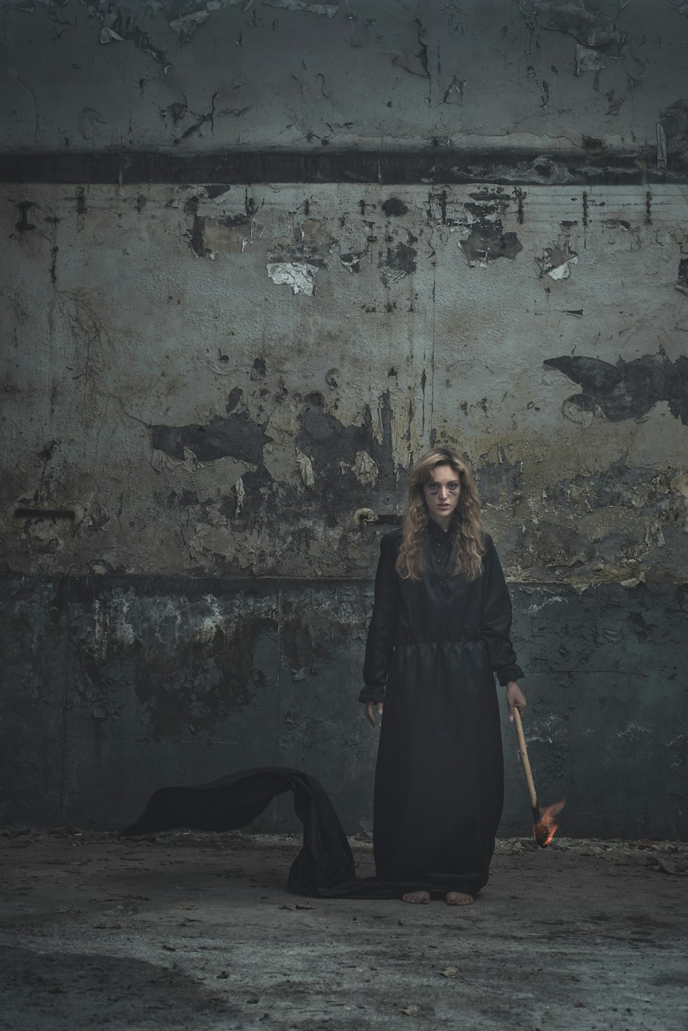 Frau im schwarzen Kleid steht vor grauer Wand