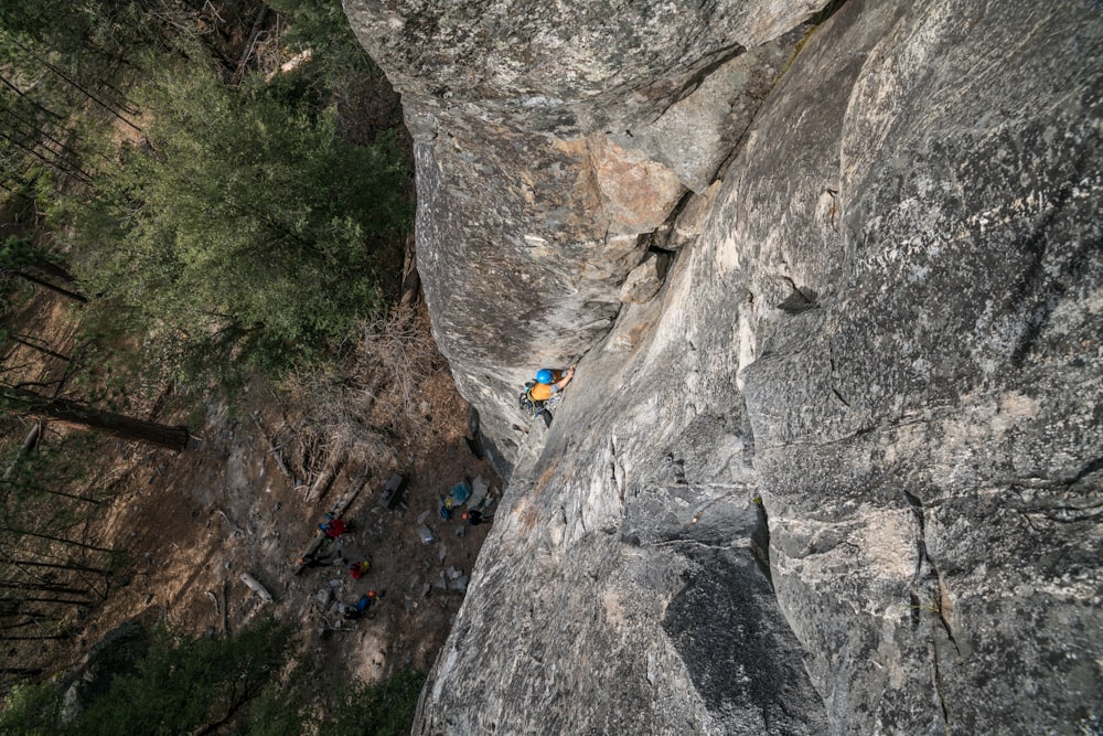 person climbing on gray rock formation at daytime