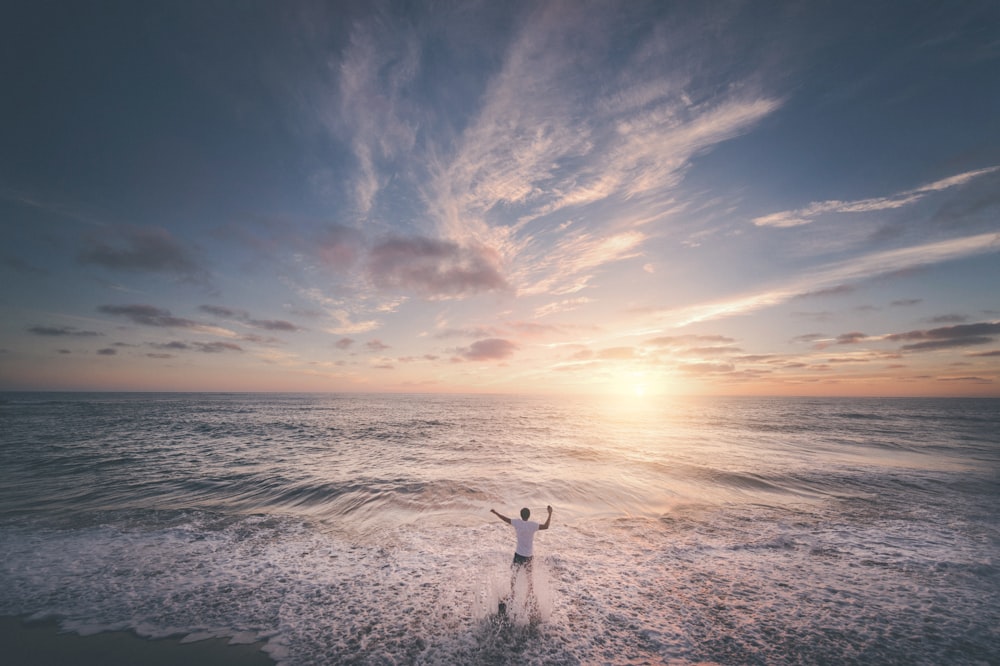 man standing on seashore during sunset