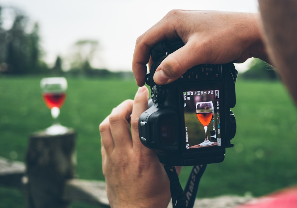 person taking photo of wine goblet