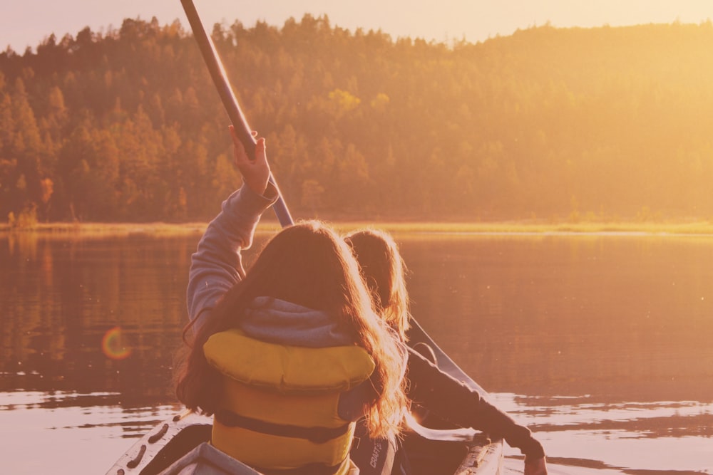 two woman riding boat on body of water