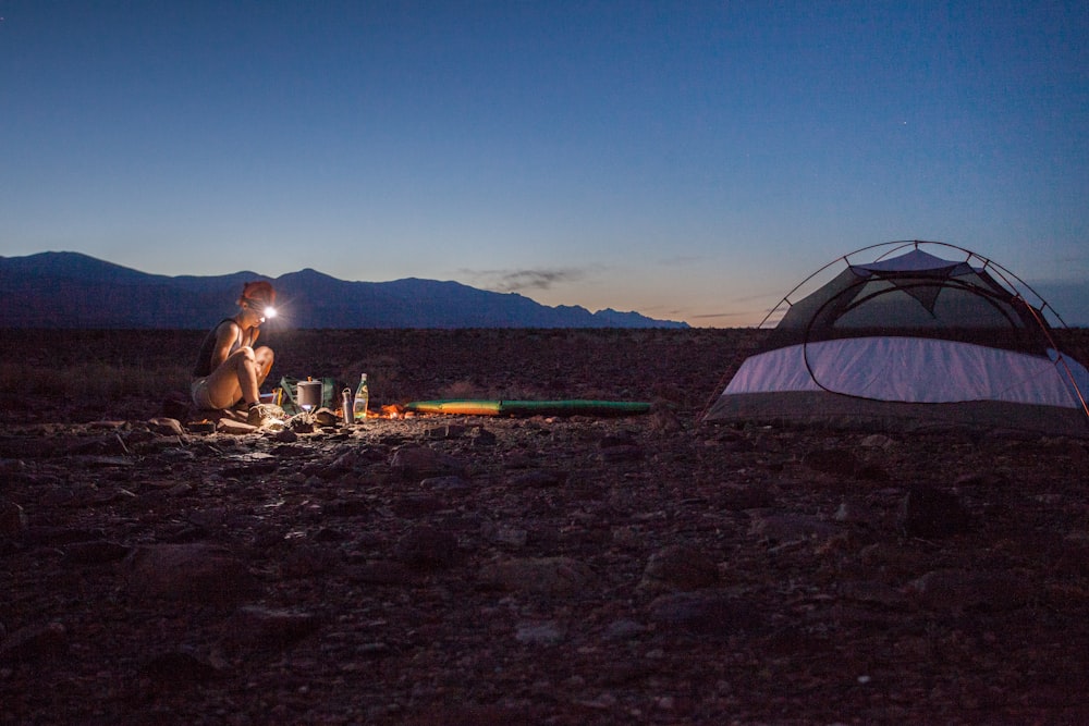 person camping beside white and black tent