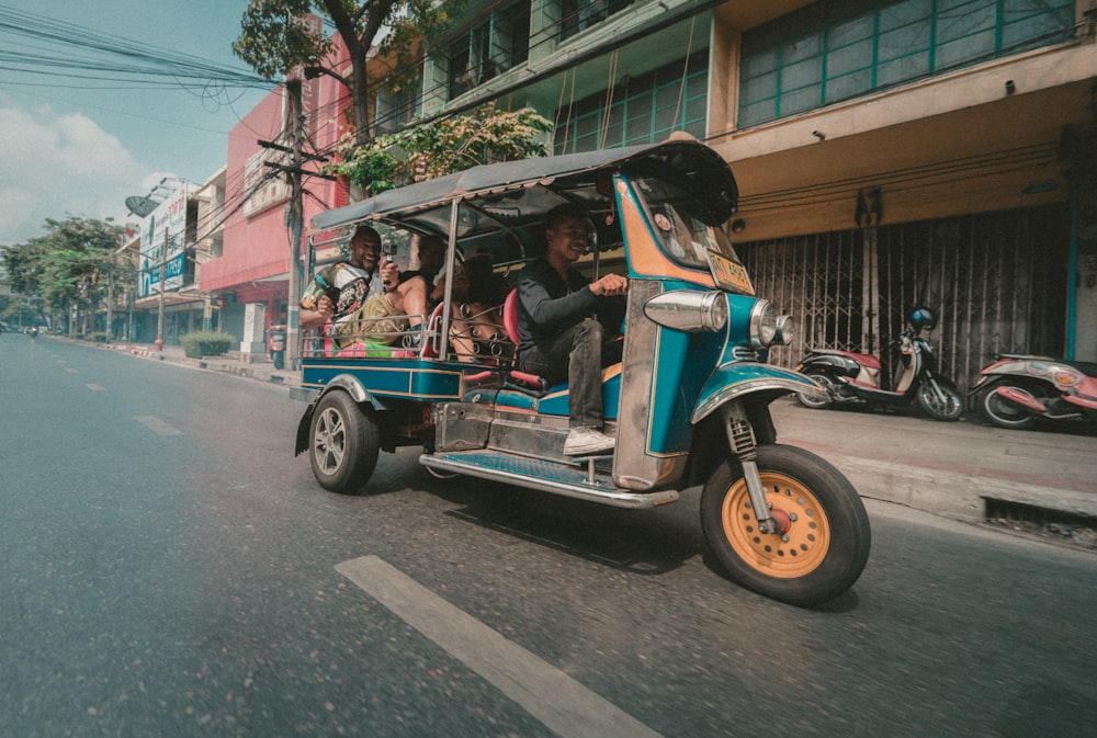 people riding in auto rickshaw near building