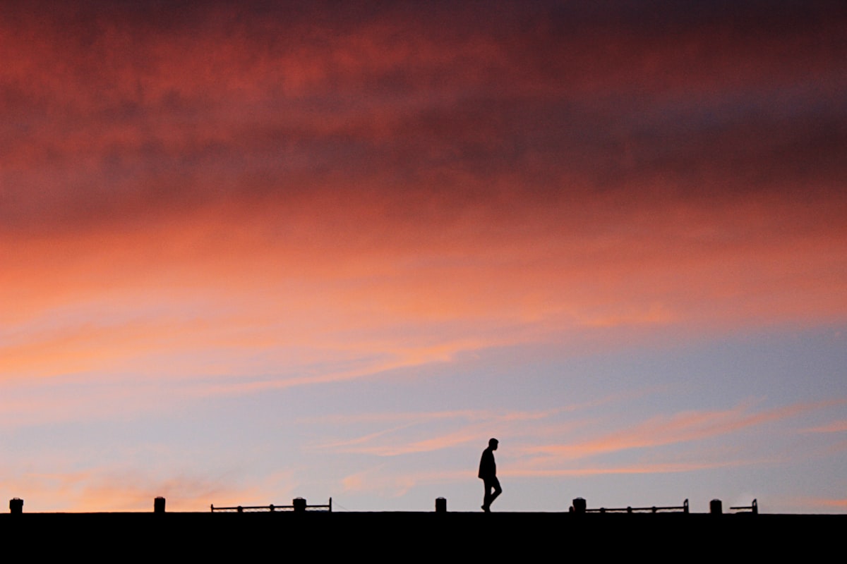 Silhouette of a person walking at sunset along the Mersey waterfront