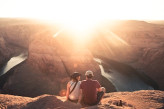 man and woman sitting on rock formation