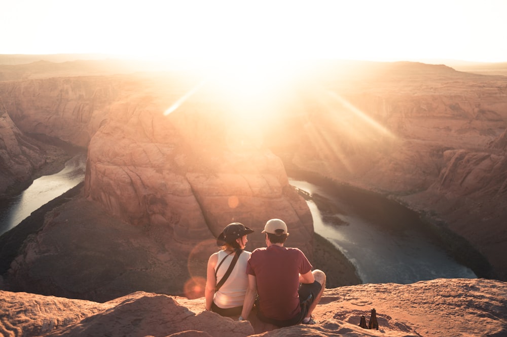 man and woman sitting on rock formation