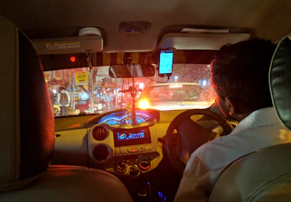 A professional driver reviewing dashcam footage on a smartphone inside a car.