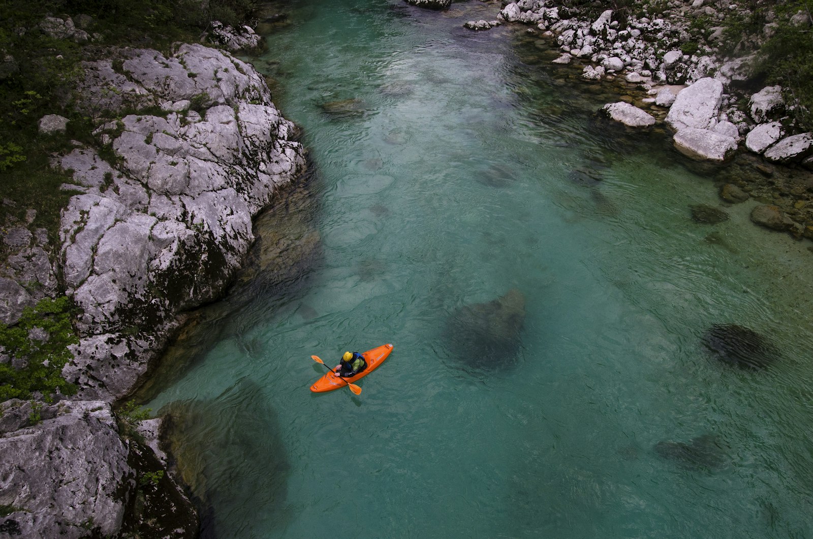 Kayak descendiendo un río de aguas turquesas entre rocas, visto desde arriba