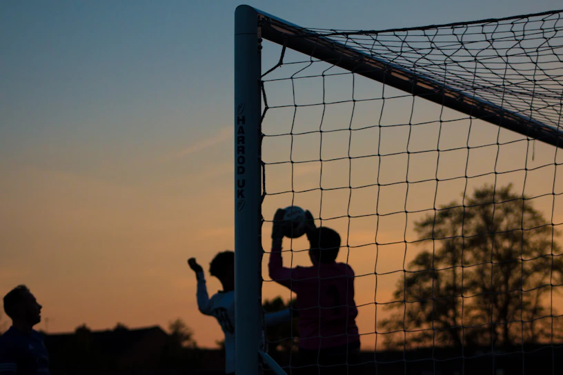 A dynamic action shot of a soccer player mid-kick during a sunset match.