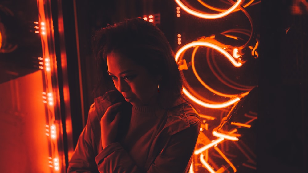 woman in gray coat standing at the front of red lights