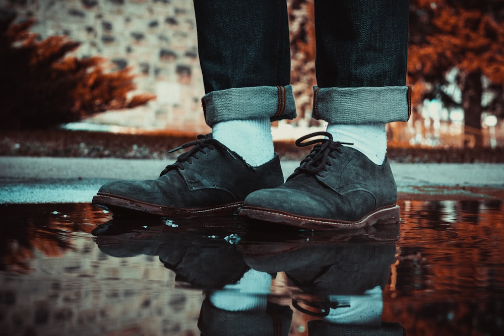 person wearing brown leather shoes stepping on water puddle