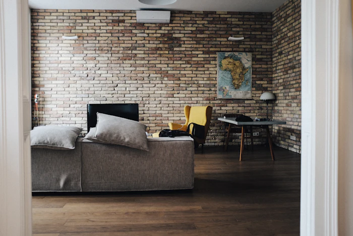 Salon avec mur de brique et canapé gris